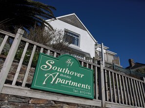 A sign for Southover Holiday Apartments with a stone wall and wooden fence in the foreground. - Woolacombe Apartment with Panoramic Sea Views (Woolacombe)