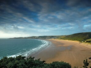 A coastal landscape with a beach, ocean, and hills. - Woolacombe Apartment with Panoramic Sea Views (Woolacombe)