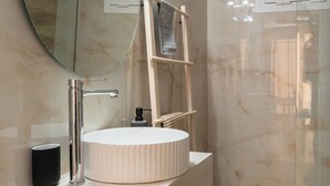 Un baño moderno con un espejo redondo, un lavabo blanco y una cabina de ducha.