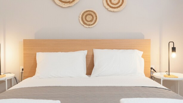 Una habitación de hotel con una cama, dos obras de arte circulares en la pared y una lámpara de noche, además de una toalla doblada sobre la cama.