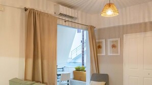 Un comedor con una mesa lista para dos personas, un sofá, una silla y una lámpara colgante.