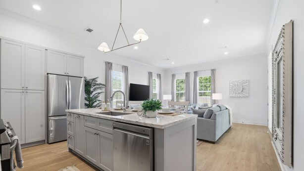 A modern kitchen with a central island, stainless steel appliances, and a dining area with a sofa.