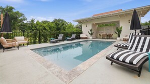 A swimming pool with lounge chairs and a covered patio area.