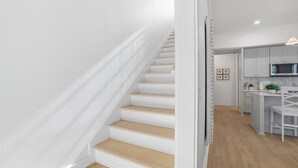 A modern interior with a staircase, a kitchen area, and a dining space.