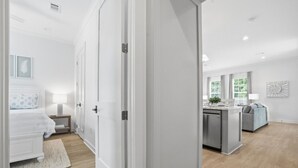 A modern interior with a bed, bedside table, lamp, and a kitchen area with a counter and cabinets.