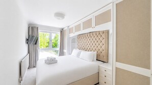 A hotel room with a large bed, a television, a window with curtains, and a radiator. - Beautiful Family Home w/ Parking in Central Oxford -Pass the Keys (Oxford)
