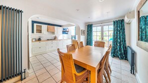 A modern kitchen with white cabinets, a dining table with wicker chairs, and a view of the outdoors. - Beautiful Family Home w/ Parking in Central Oxford -Pass the Keys (Oxford)