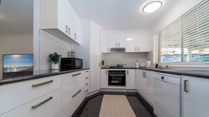 Eine moderne Küche mit weißen Schränken, einer schwarzen Arbeitsplatte und einem eingebauten Backofen.