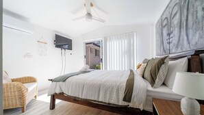 Ein Schlafzimmer mit Bett, einer Couch, einem Fernseher und einem Deckenventilator.