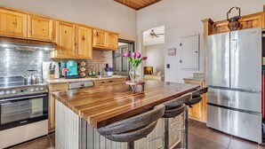 A modern kitchen with wooden cabinets, stainless steel appliances, and a central island with bar stools. - Historic Garden Flat w/ Screened Porch and Court Yard, Walk to Forsyth & Squares (Savannah)