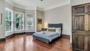 A bedroom with a large bed, a nightstand, a lamp, and a window with blinds. - Historic Garden Flat w/ Screened Porch and Court Yard, Walk to Forsyth & Squares (Savannah)