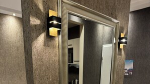 A bedroom with a large mirror, a bed with white and red bedding, and a view of a kitchen and bathroom through an open door. - Suity-Centrum (Hamburg)