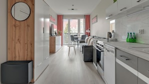 A modern kitchen with a dining area, wooden paneling, and a clock on the wall. - Mostek 2101 PinkGray by Grand Apartments (Gdańsk)
