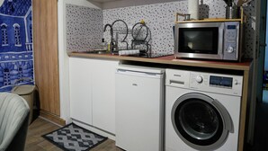 Une petite cuisine équipée d’un four à micro-ondes, d’un lave-vaisselle et d’un lave-linge.