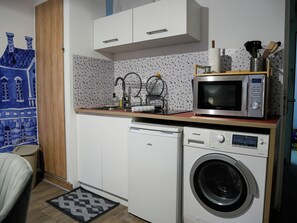 Eine kleine Küchenzeile mit Mikrowelle, Geschirrspüler und Waschmaschine.