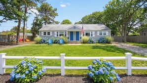 A house with a front porch, a flag, and a white fence. - Waterview Half-Duplex -Walk 2 Seagull Beach/Kayaks (Yarmouth)