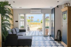 A modern room with a sofa, a guitar, and a view of the outdoors. - Modern Studio in the Eurotennis Resort (La Vila Joiosa)