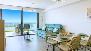A modern living room with a sofa, dining table, chairs, and a city view. - Exclusive Apartment. Relax, Luxury and Sea Views (Finestrat)