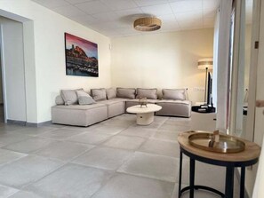 Ein modernes Wohnzimmer mit einer Eckcouch, einem runden Couchtisch und einem Bild an der Wand.