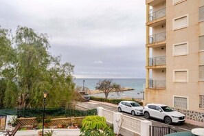 Ein Wohngebäude mit Balkonen, Blick auf das Meer und parkenden Autos.