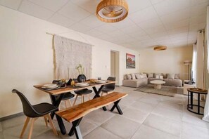 Ein Essbereich mit Holztisch, schwarzen Stühlen und einer Bank. Im Wohnbereich befindet sich eine Couch und ein Couchtisch.