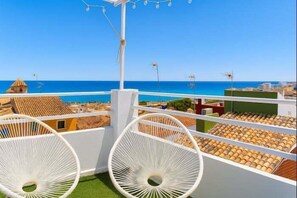A balcony with white wicker chairs, a view of the sea, and buildings with red-tiled roofs. - Modern loft with sea views (La Vila Joiosa)