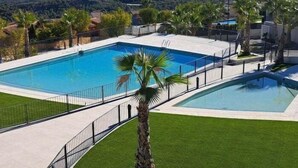 A rectangular swimming pool with a surrounding deck, palm trees, and a mountainous backdrop. - Beautiful villa with private pool and sea views (Polop)