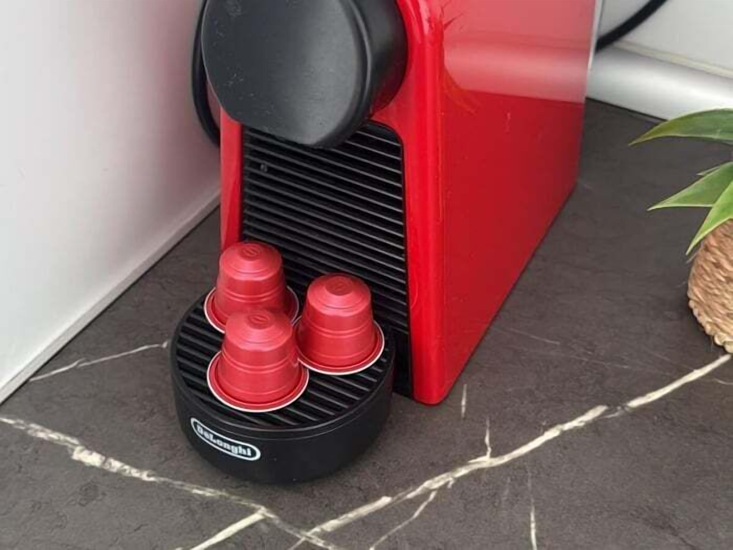 Eine rote und schwarze Kaffeemaschine mit zwei roten Tassen auf einem gefliesten Boden.