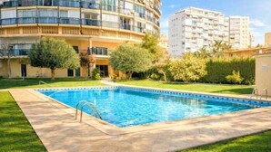 Une piscine dotée d’une terrasse carrelée, entourée d’une pelouse bien entretenue et d’arbres.