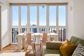 A room with a large window, a dining table with chairs, and a sofa. - Renovated central apartment with garage and pool (Benidorm)