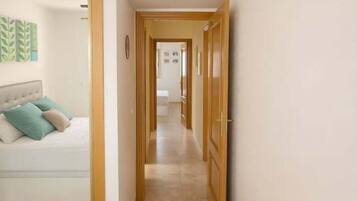 A hallway leading to a bedroom with a bed and a nightstand.