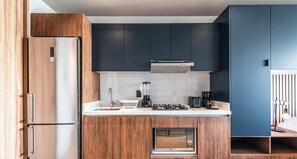 A modern kitchen with a built-in microwave, a coffee maker, and a blender on the countertop. - Loft con balcón y cocineta (Ciudad de México)