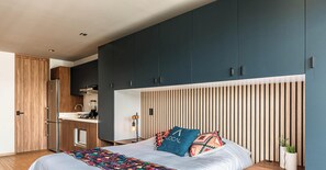 A bedroom with a bed, a bedside table, a nightstand, a dresser, and a built-in desk with a chair. - Loft con balcón y cocineta (Ciudad de México)