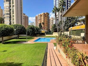 A residential area with a swimming pool, green lawns, and tall buildings in the background. - Apartment with Sea Views and Covered Parking (Benidorm)
