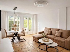 Ein modernes Wohnzimmer mit einer Couch, einem Esstisch mit Stühlen und einem runden Couchtisch.