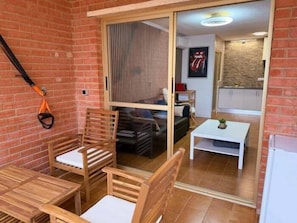 Ein Zimmer mit einer Schiebetür zum Küchenbereich, einem Holztisch und Stühlen sowie einem Deckenventilator.