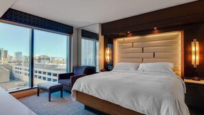 Een moderne hotelkamer met een groot bed, een zithoek en uitzicht over de stad.
