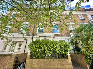 A multi-story building with brick walls, white trim, and multiple windows. - Luxe modern Penthouse with A/C and two large beds.  Great location (London)