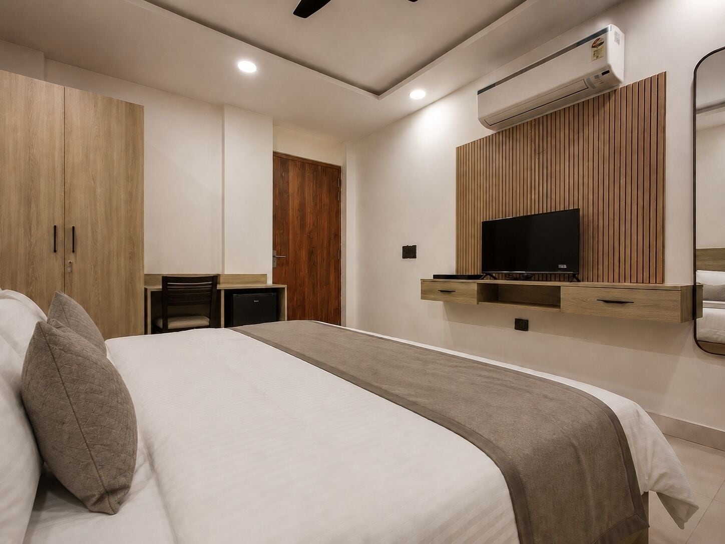 Una habitación de hotel moderna con cama, televisor, armario, escritorio y aire acondicionado.