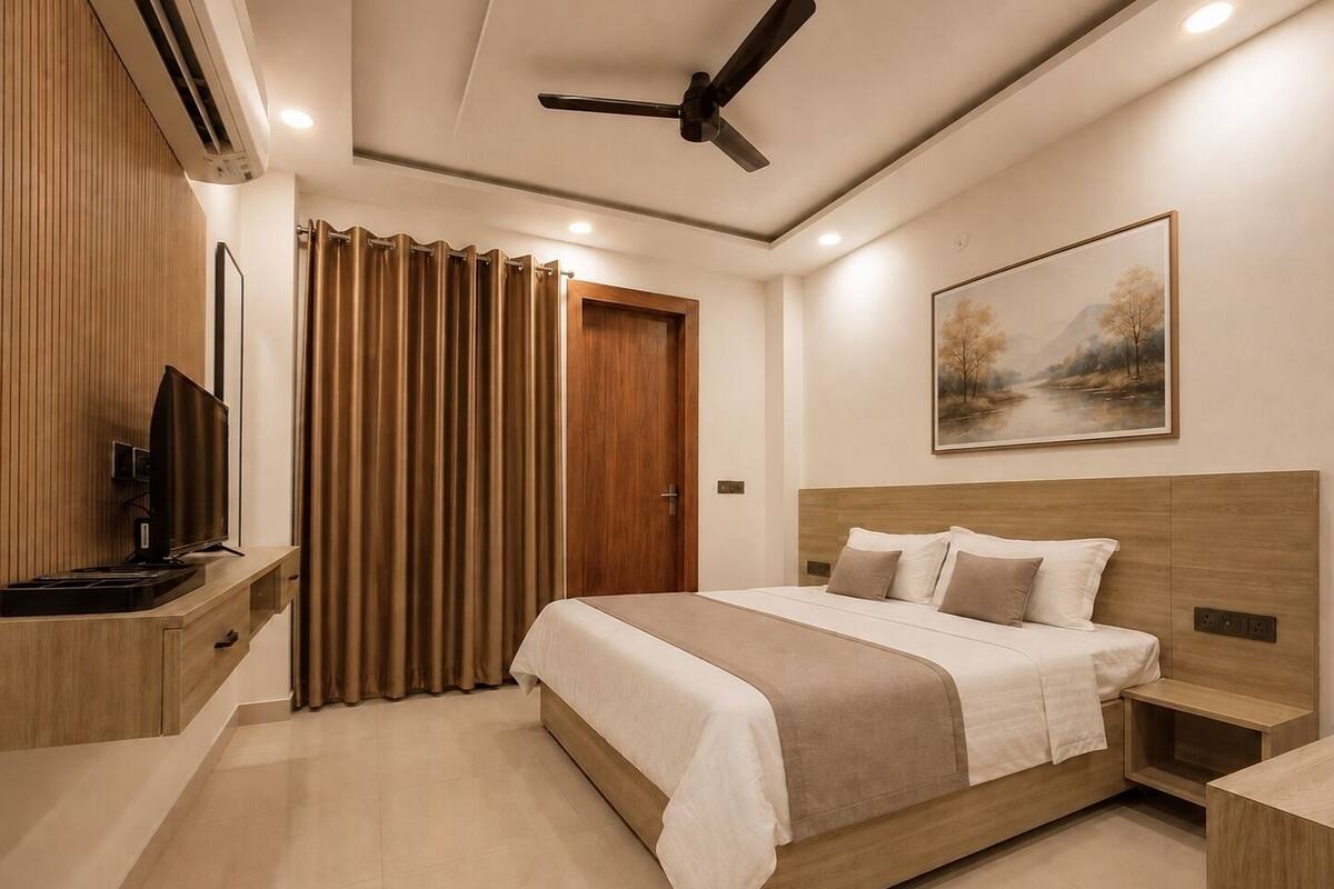 Habitación de hotel moderna con cama, mesita de noche, televisor y ventilador de techo.