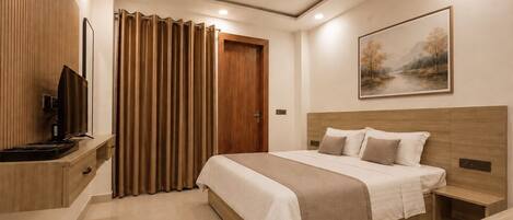 A modern hotel room with a bed, bedside table, TV, and a ceiling fan.