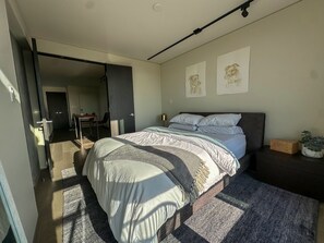 Ein modernes Schlafzimmer mit einem großen Bett, einem Schreibtisch und einem Stuhl im angrenzenden Raum.