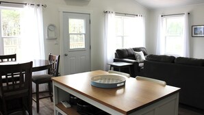 Un espacio habitable compacto con zona de comedor, un sofá y una pequeña mesa con un plato decorativo.