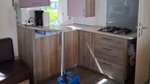 Eine kleine Küche mit Holzausstattung, einem Gasherd und einem Backofen.