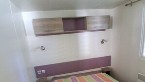 Ein kleines Schlafzimmer mit einem Bett, einem Nachttisch, einem Regal über dem Bett und einem Fenster.