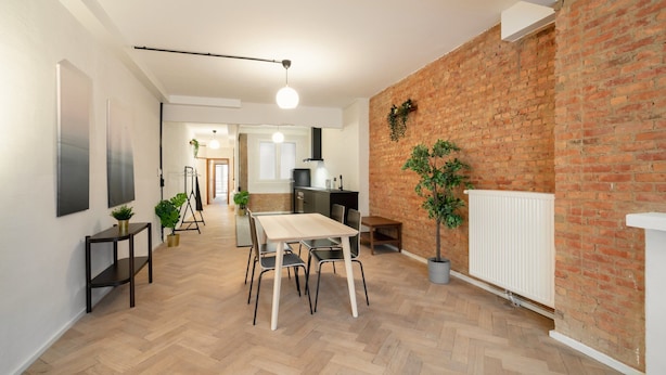 Una cocina moderna con pared de ladrillo, suelo de madera y una zona de comedor con mesa y sillas.