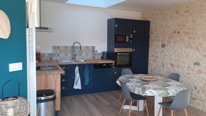 Una cucina compatta con zona pranzo, un muro in pietra e una finestra.