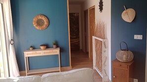 Una stanza con una parete blu, un tavolino consolle in legno con piante, un cesto di vimini e una porta che dà su un'altra stanza.