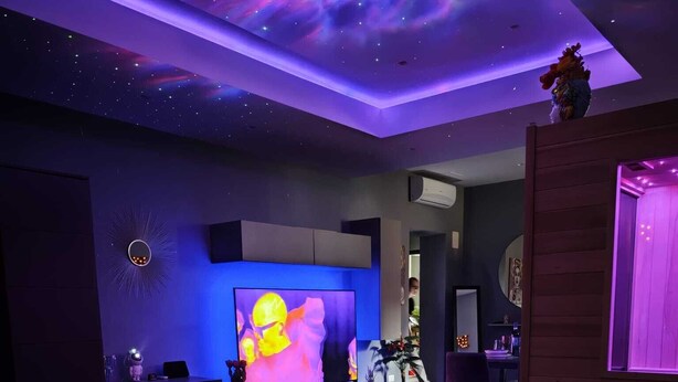 Ein Zimmer mit einem großen Flachbildfernseher, einer Sternenhimmel-Decke und einem Bett mit Handtüchern und einer herzförmigen Dekoration.