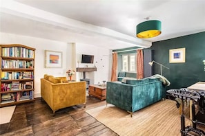 Ein Wohnzimmer mit Bücherregal, zwei Sofas, einem Fernseher und einem Fahrrad.